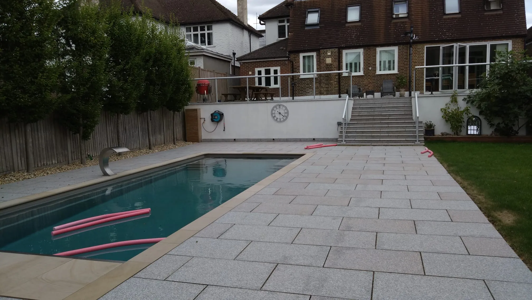 A backyard with a swimming pool and steps leading to a house.